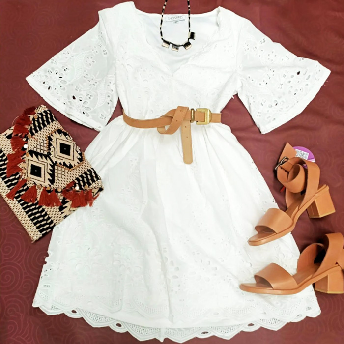 flatlay of white frilly dress and tan strappy sandals paired with a tan bag
