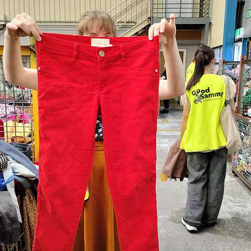 Student holding up red jeans in the Good Sammy Factory Outlet