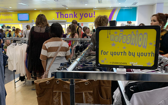 Close up of ReFashion sign and people in the background shopping the youth racks.