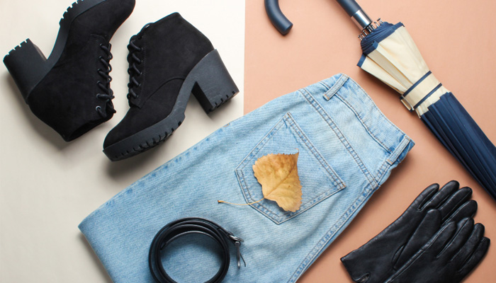 Flatlay of items including jeans, belt, umbrella and leather gloves