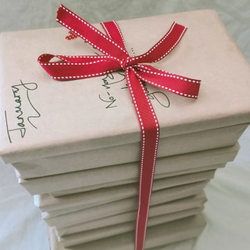 Books neatly wrapped in recycled brown paper with handwritten description of what's inside.
