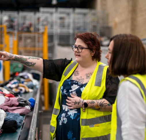 2 ladies talking next to conveyor belt of clothes
