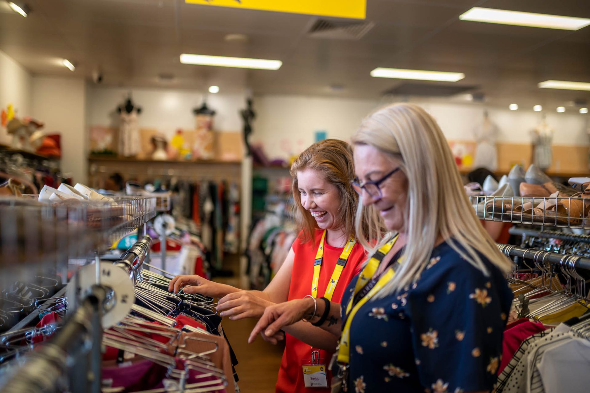 Two female Good Sammy shops employees merchandising clothing.