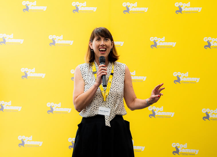 Mayor Hannah Fitzhardinge with a beaming smile in front of the good sammy presentation wall