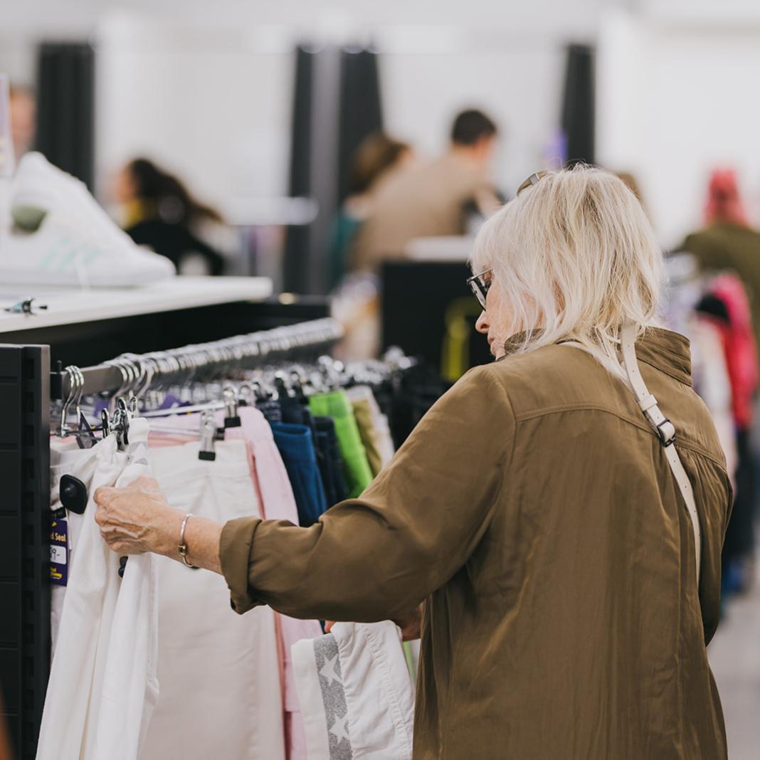 A woman browsing through a rack of clothing.