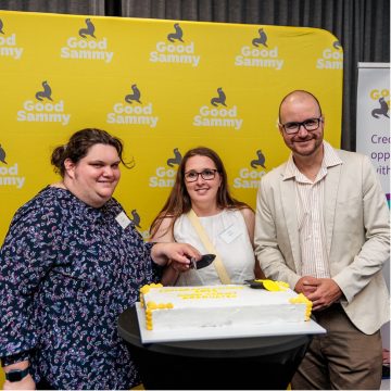 Three people standing around a large cake.